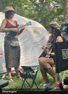 Two women playing mandolins at their campsite