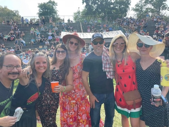 Friends standing in a row and posing for a picture in the stage area at the Watermelon Pickers' fest