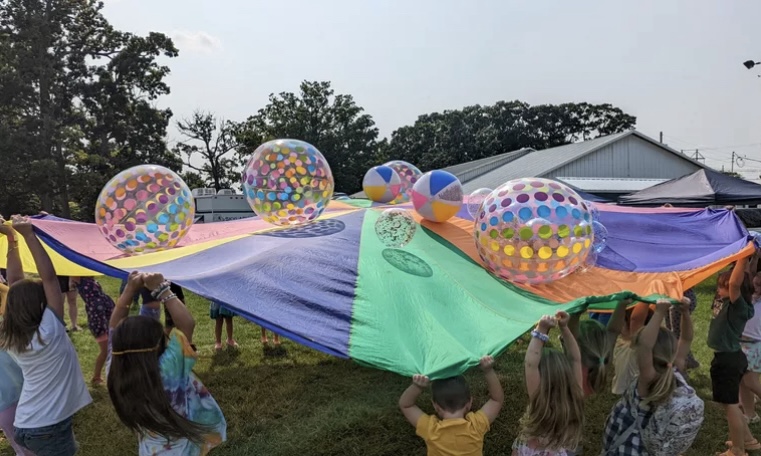 Children playing with a parachute and bouncing beach balls on it