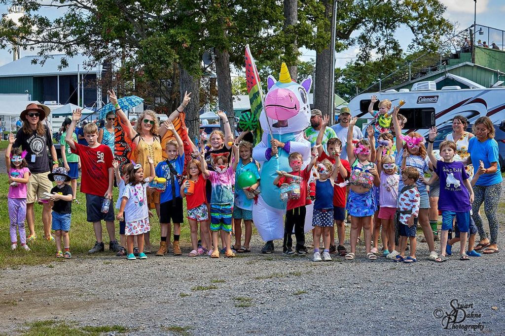 Kids parading through the fairgrounds with a person in an inflatable unicorn costume