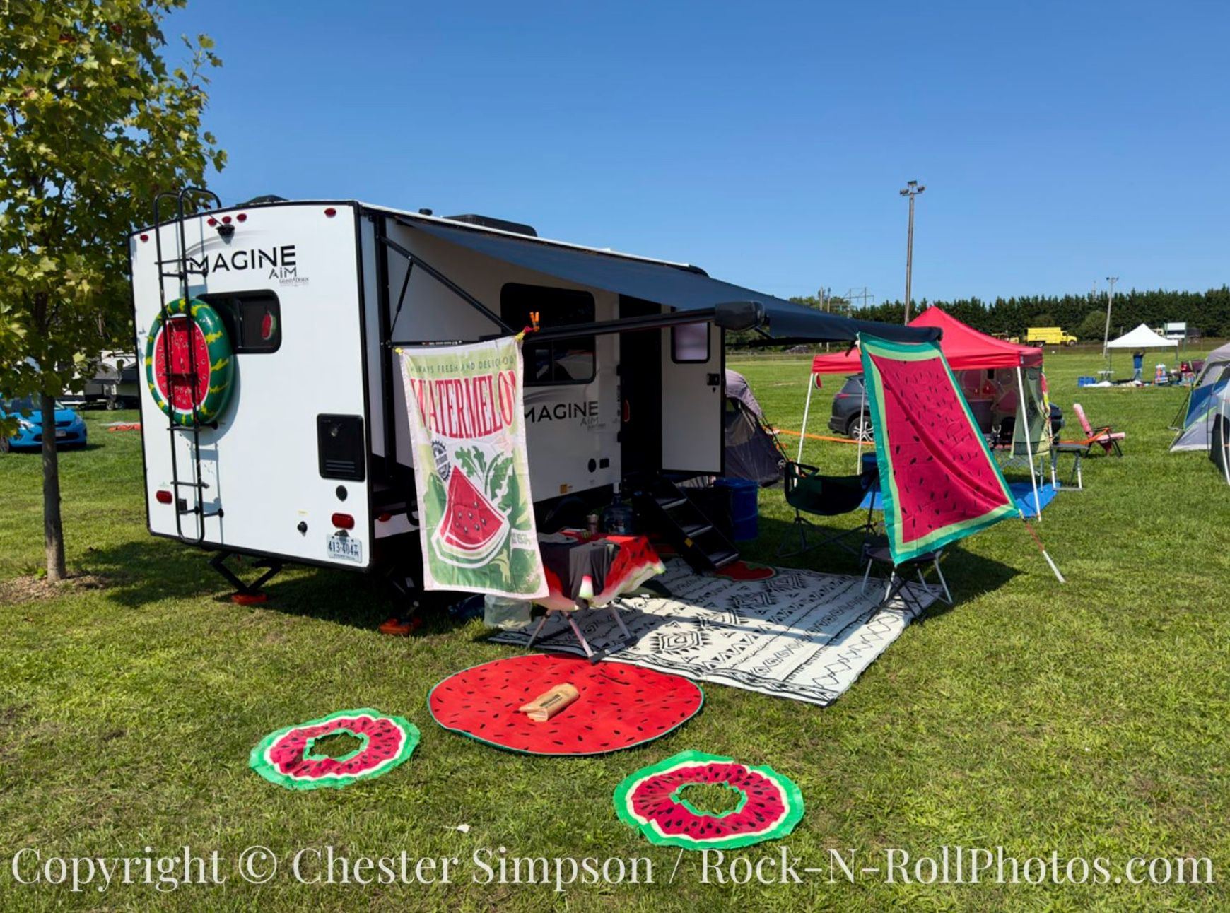 a camper set up at the fairgrounds with watermelon themed decor, flags, and so on