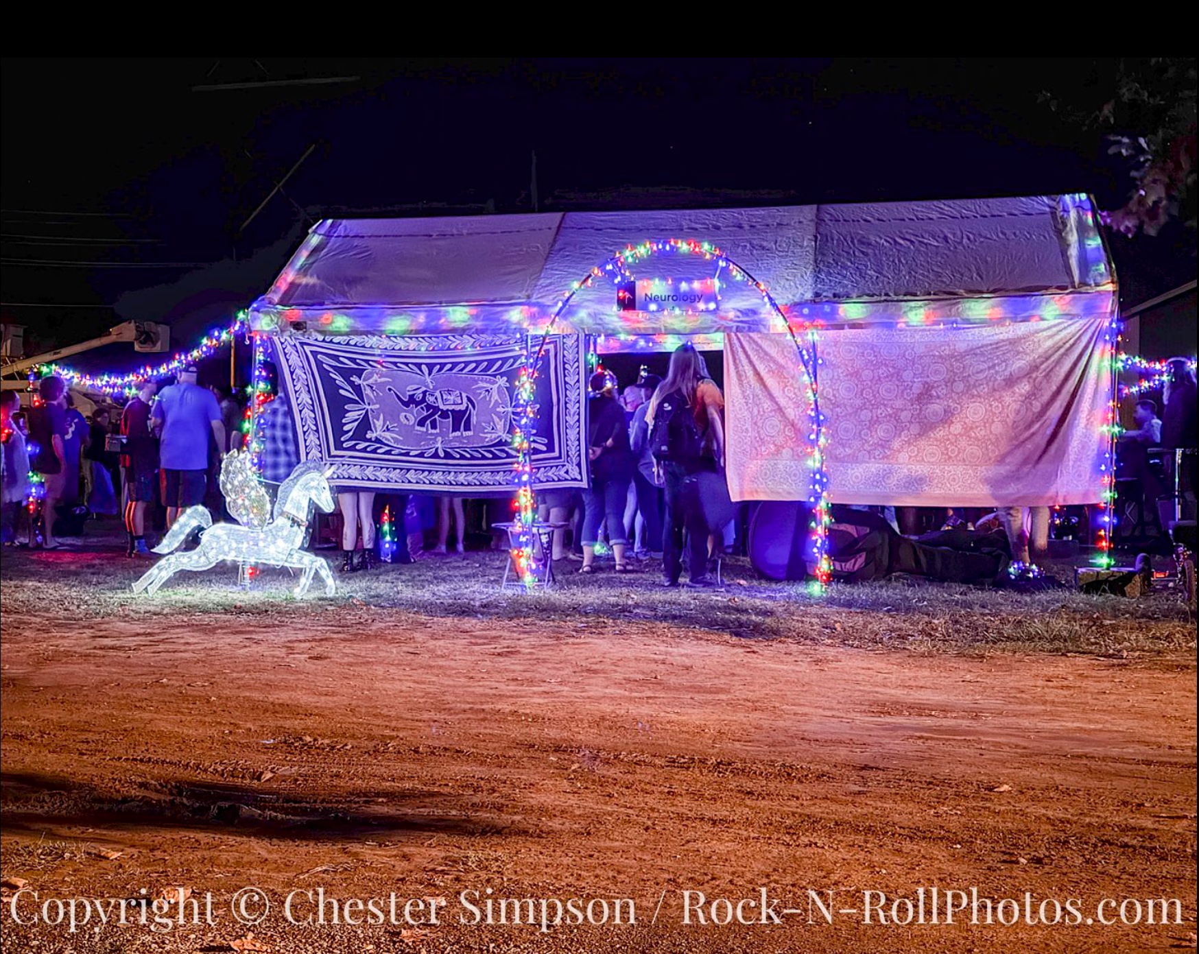 Neurology – photo by Chester Simpson The Neurology Jam Tent lit up at night, filled with pickers and observers