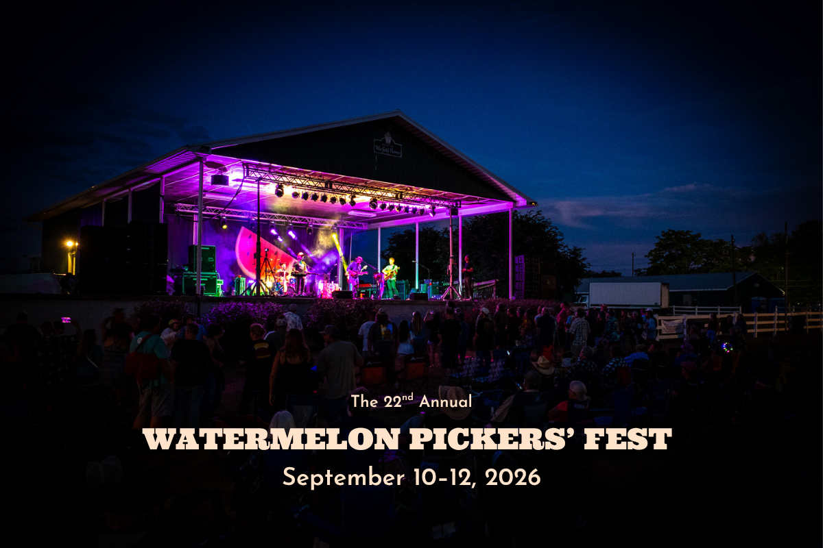 Image of the Watermelon Pickers' Fest stage illuminated for a performance , with a crowd in front and a band onstage